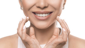 Close up portrait of a smiling woman over white background. Teeth whitening and stomatology concept