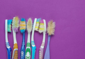 Old used toothbrushes on purple background. Top view