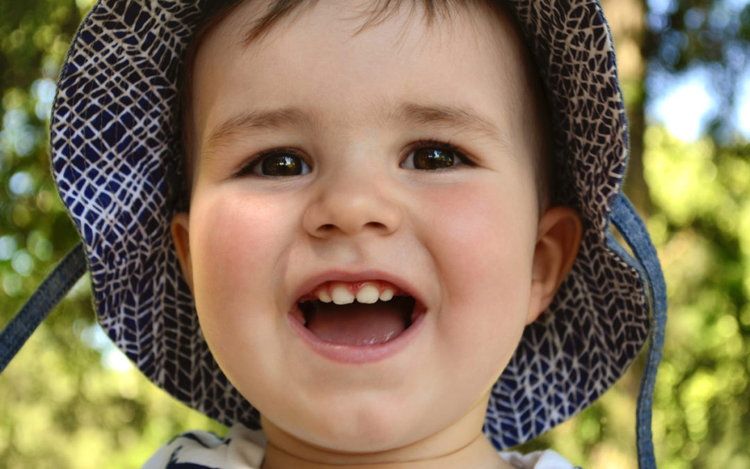 Portrait of a joyful baby with a smile in a summer hat with fields.