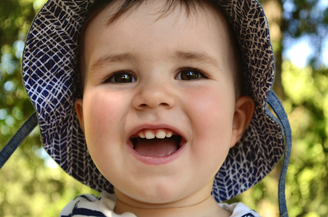 Portrait of a joyful baby with a smile in a summer hat with fields.