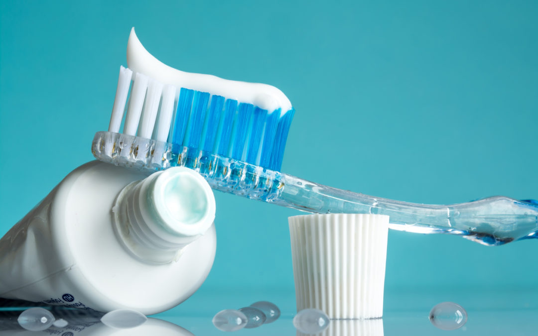New toothbrush with toothpaste close-up in the bathroom on a mirror table with water drops on a blue background in the sunlight