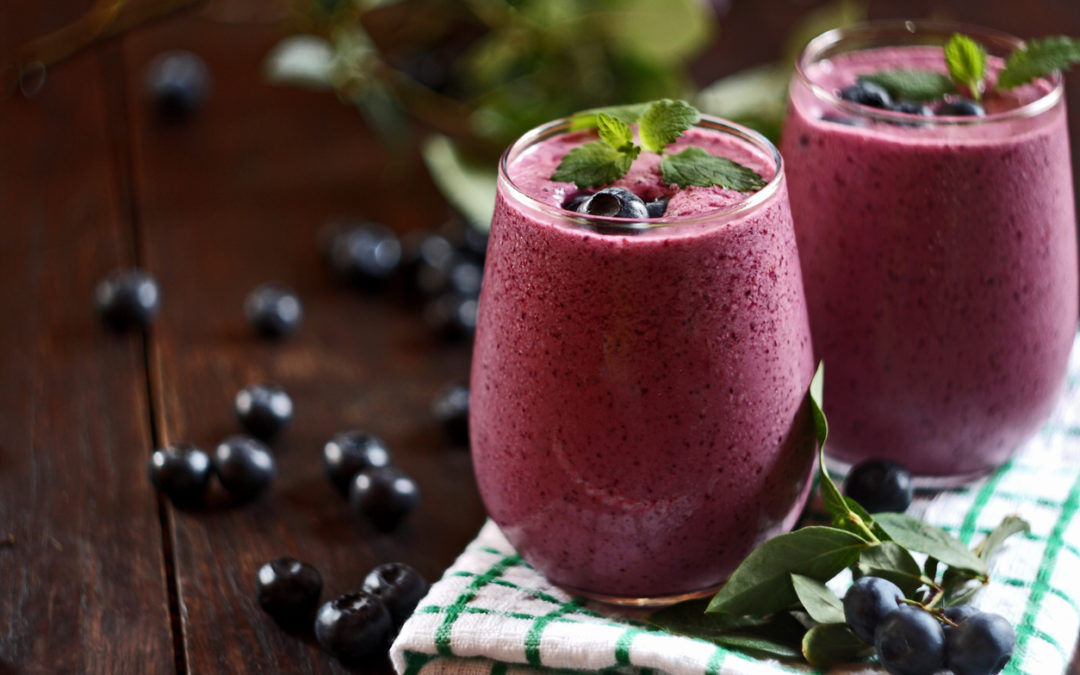 Two glasses of blueberry smoothie on wooden background. Selective focus